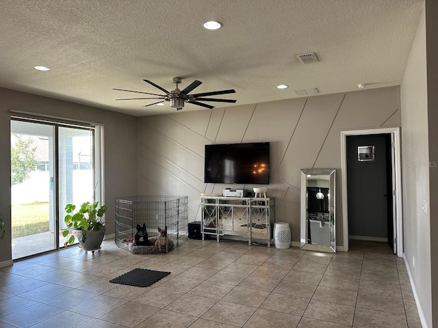 living room with a textured ceiling, light tile patterned floors, and ceiling fan