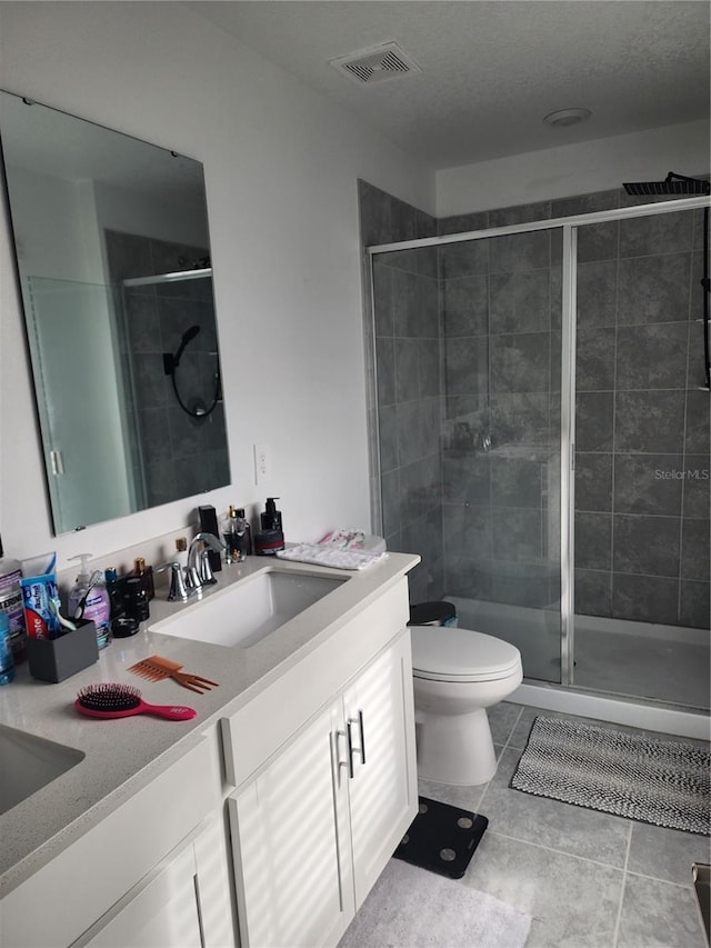 bathroom featuring walk in shower, vanity, toilet, and tile patterned flooring