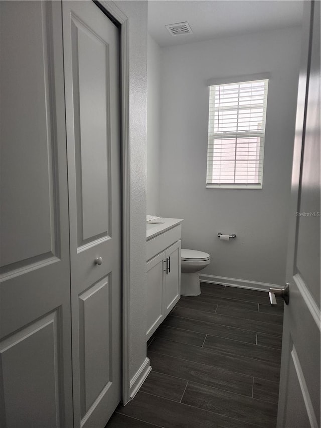 bathroom featuring toilet, vanity, and hardwood / wood-style floors