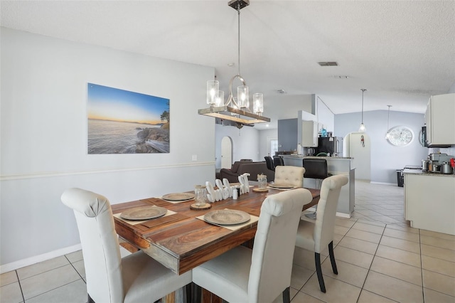 tiled dining space featuring a textured ceiling and vaulted ceiling