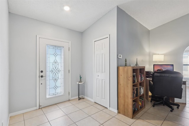 tiled foyer with vaulted ceiling and a textured ceiling