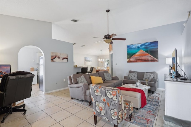 tiled living room featuring ceiling fan with notable chandelier