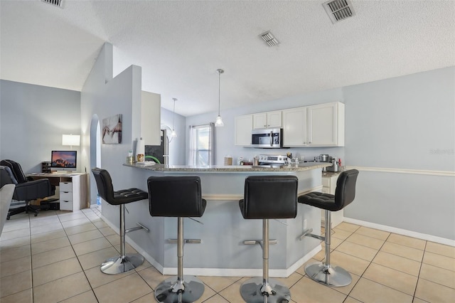 kitchen with white cabinets, a kitchen bar, kitchen peninsula, and stainless steel appliances