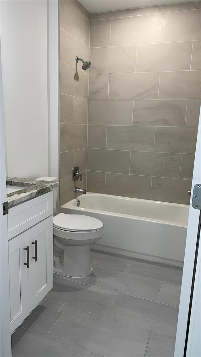 full bathroom with vanity, tiled shower / bath combo, and toilet