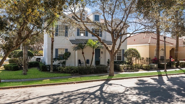 view of front of house with cooling unit and a front lawn