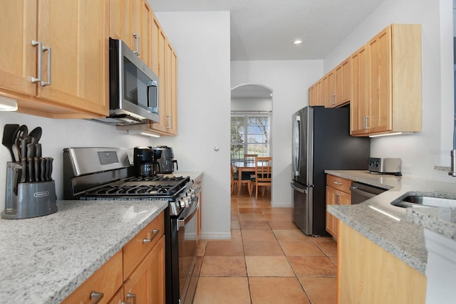 kitchen featuring light brown cabinetry, appliances with stainless steel finishes, light stone counters, and light tile patterned flooring