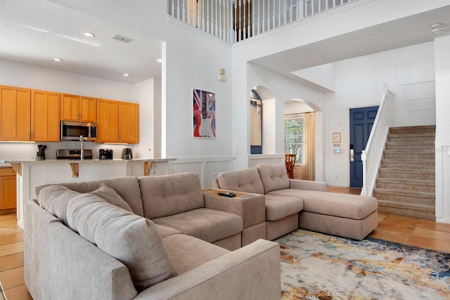 living room featuring a textured ceiling, a towering ceiling, and light tile patterned floors