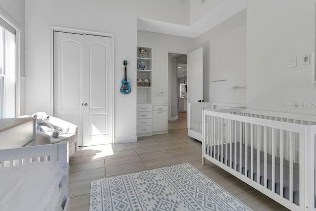 bedroom with a crib, a closet, and light tile patterned floors