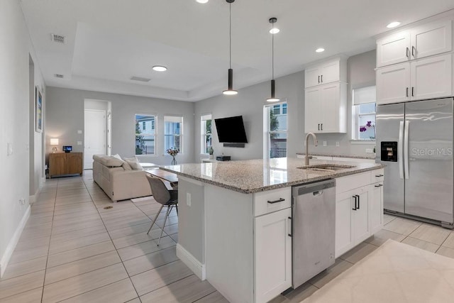 kitchen with white cabinetry, stainless steel appliances, sink, and an island with sink