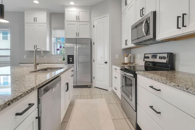 kitchen with sink, decorative light fixtures, white cabinetry, appliances with stainless steel finishes, and light stone counters