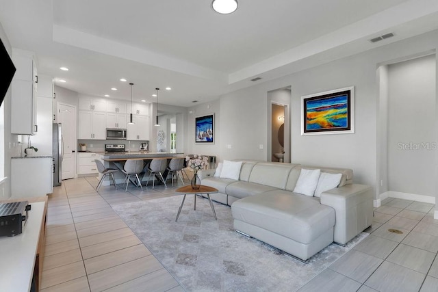 living room with a raised ceiling and light tile patterned flooring