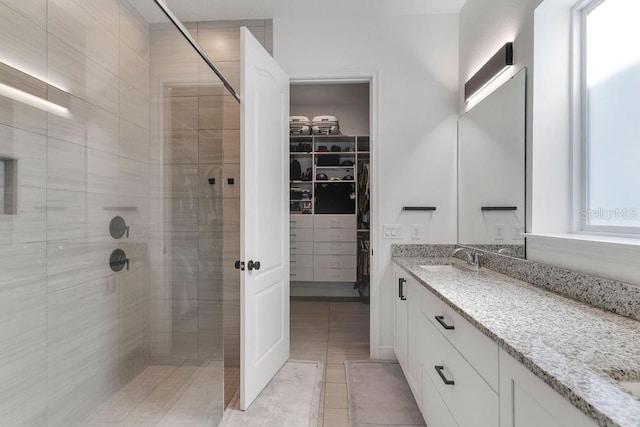 bathroom featuring vanity, a tile shower, and tile patterned flooring