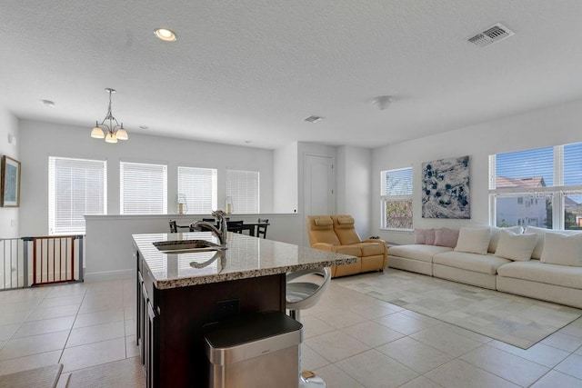 kitchen with decorative light fixtures, sink, a wealth of natural light, and a center island with sink