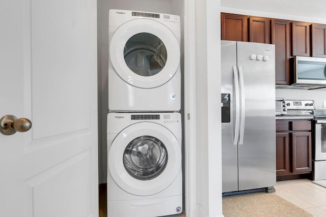 washroom with stacked washer and dryer and light tile patterned floors