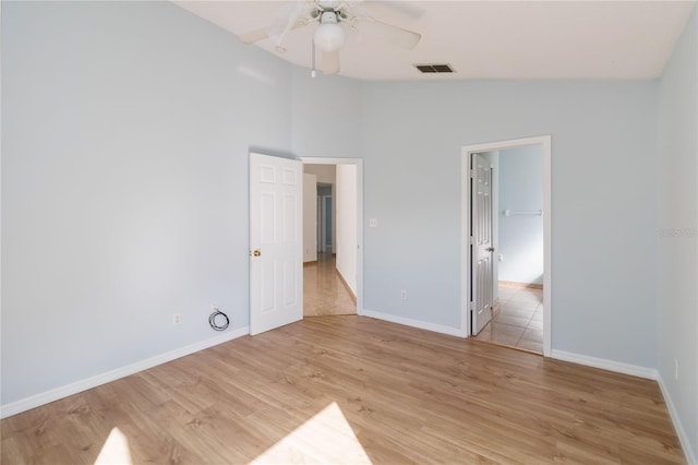 unfurnished bedroom featuring a spacious closet, lofted ceiling, light hardwood / wood-style flooring, and ceiling fan