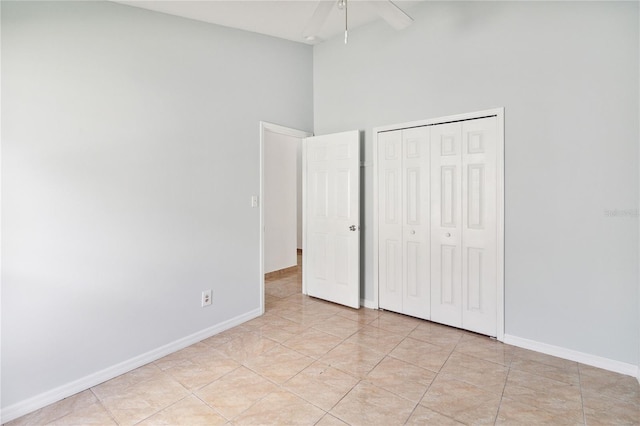 unfurnished bedroom with a closet, light tile patterned flooring, a high ceiling, and ceiling fan