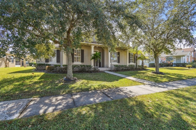 view of property hidden behind natural elements featuring stucco siding and a front yard