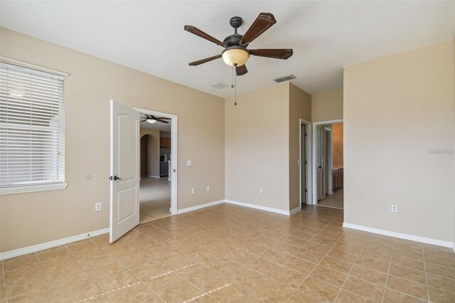 unfurnished room with arched walkways, baseboards, visible vents, a ceiling fan, and light tile patterned floors