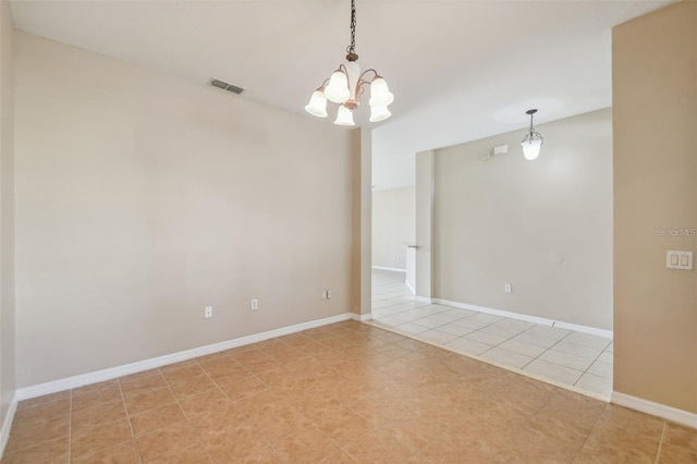 tiled spare room with a chandelier