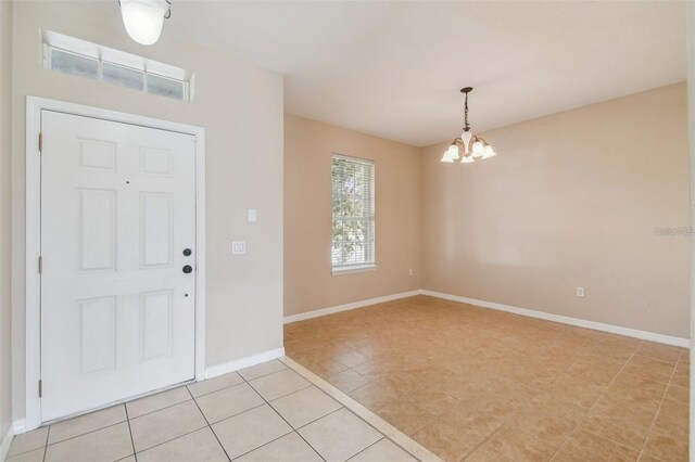 foyer entrance with baseboards, a chandelier, and light tile patterned floors