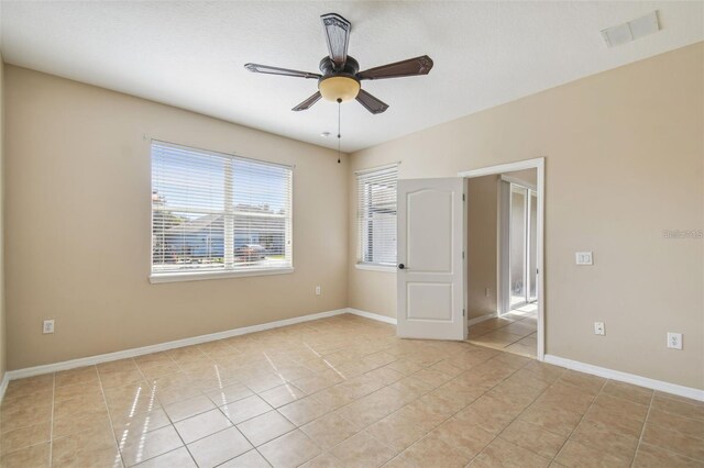 unfurnished room with visible vents, a ceiling fan, baseboards, and light tile patterned floors