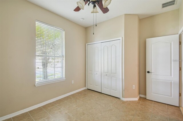 unfurnished bedroom with a closet, light tile patterned flooring, ceiling fan, baseboards, and visible vents
