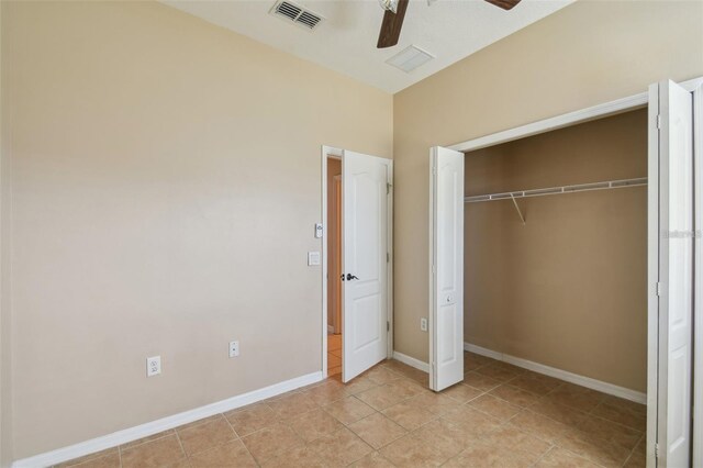 unfurnished bedroom featuring visible vents, light tile patterned flooring, a closet, baseboards, and ceiling fan