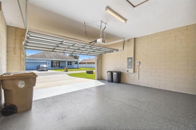 garage with electric panel, a garage door opener, and concrete block wall