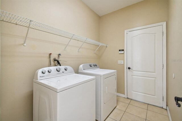 laundry room with washing machine and clothes dryer, baseboards, laundry area, and light tile patterned floors