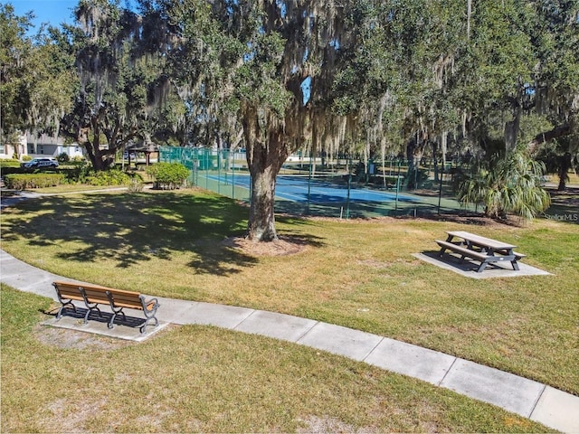 view of home's community with tennis court and a lawn