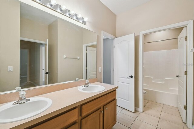 bathroom with double vanity, tile patterned floors, toilet, and a sink