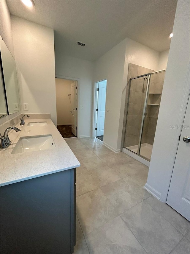 bathroom featuring a shower with door, vanity, and tile patterned floors