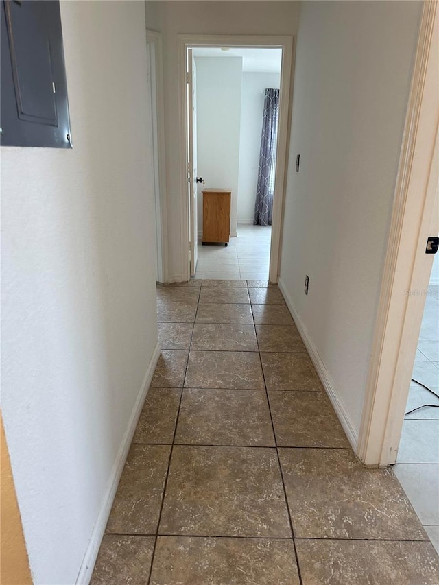 hallway with electric panel and dark tile patterned flooring