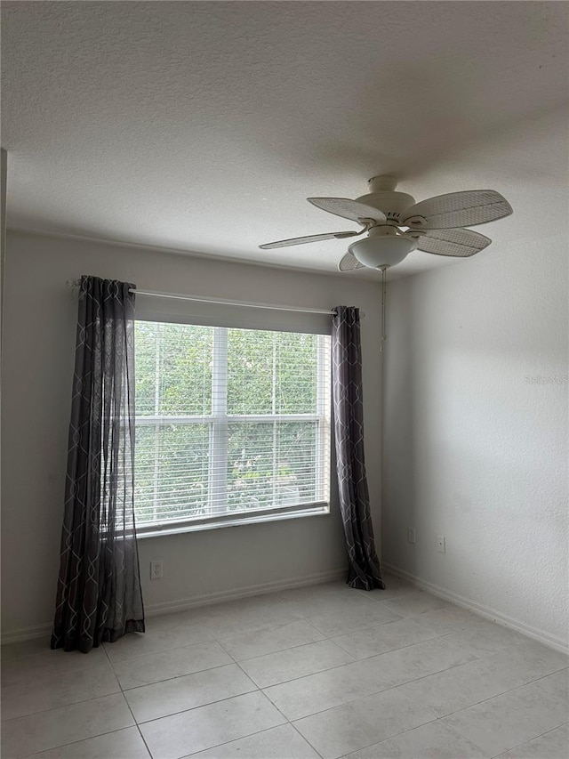 unfurnished room with ceiling fan, a textured ceiling, and light tile patterned floors