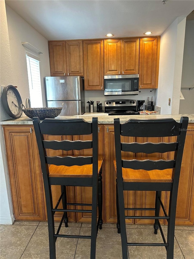 kitchen featuring a kitchen breakfast bar, stainless steel appliances, and light tile patterned floors