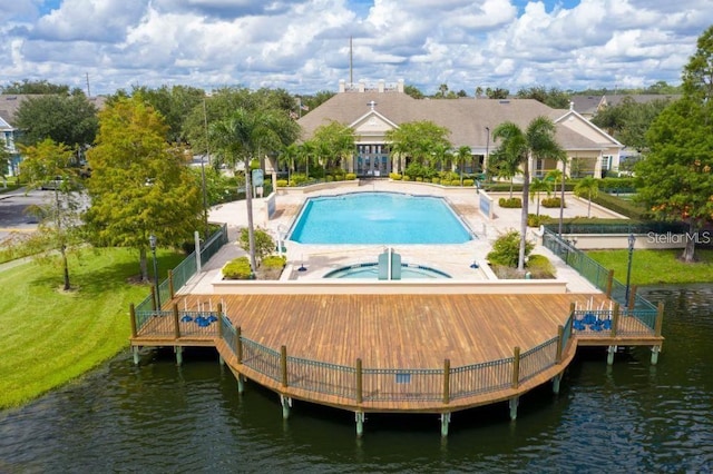 view of pool with a jacuzzi, a deck with water view, a yard, and a patio area