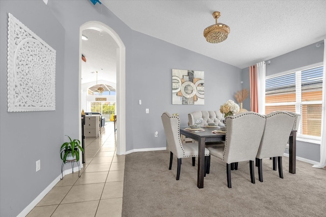 tiled dining room with a wealth of natural light, vaulted ceiling, and a textured ceiling