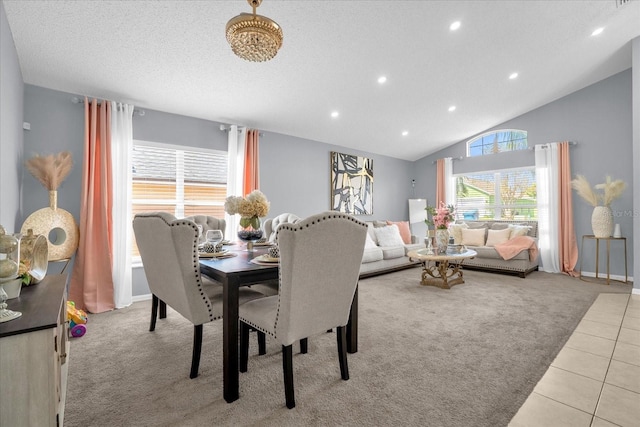 dining space with a textured ceiling, vaulted ceiling, and light colored carpet