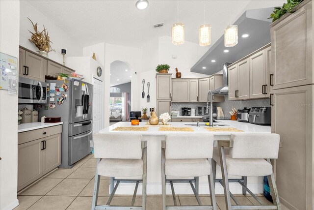 kitchen with a kitchen breakfast bar, hanging light fixtures, gray cabinetry, stainless steel appliances, and light tile patterned flooring