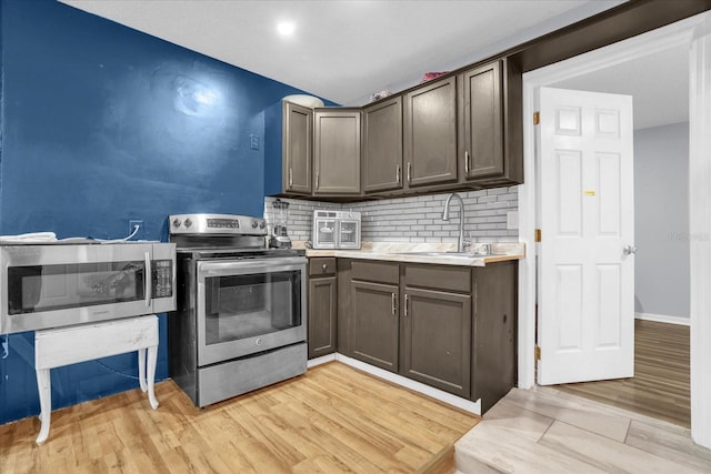 kitchen featuring light hardwood / wood-style floors, stainless steel appliances, dark brown cabinets, and decorative backsplash