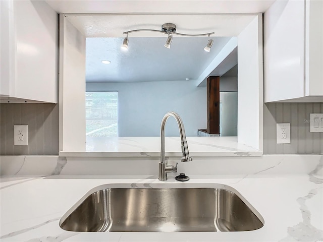 details with track lighting, sink, white cabinetry, and light stone counters