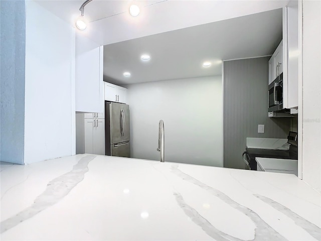 kitchen featuring light stone countertops, sink, appliances with stainless steel finishes, and white cabinetry