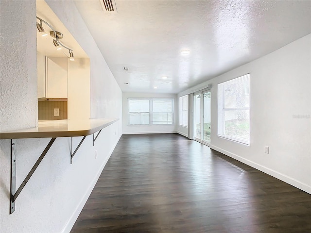 unfurnished living room featuring dark wood-type flooring and a textured ceiling