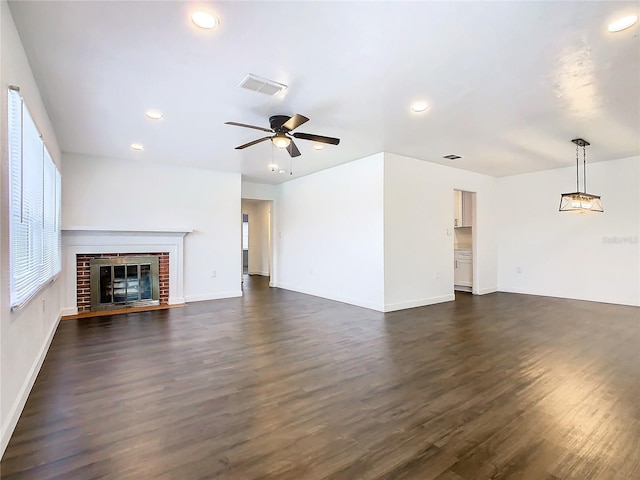 unfurnished living room featuring dark wood-type flooring, a fireplace, and ceiling fan