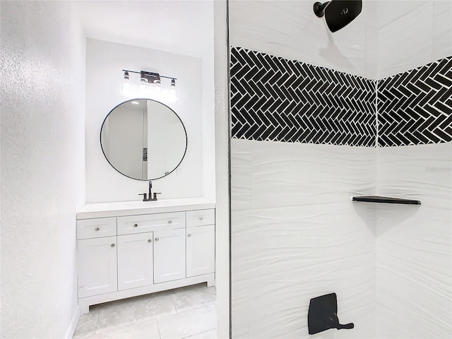 bathroom with vanity, tiled shower, and tile patterned flooring