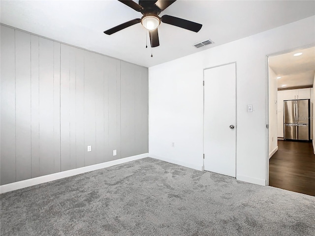 spare room with dark colored carpet and ceiling fan