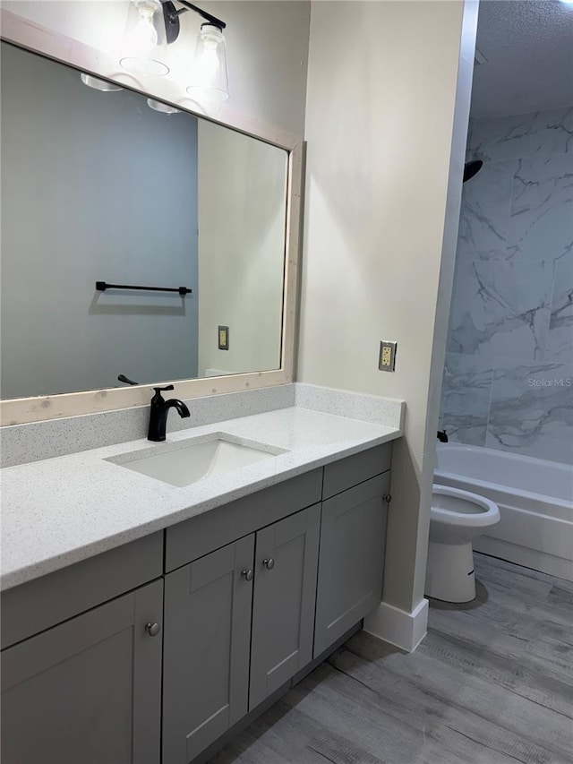 bathroom with toilet,  shower combination, wood finished floors, and vanity