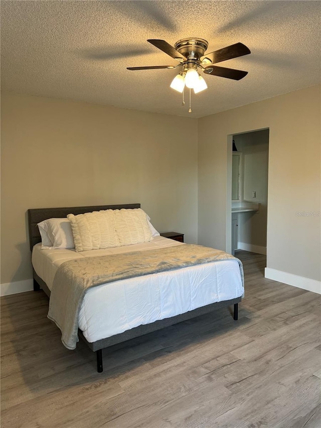 bedroom with a textured ceiling, a ceiling fan, baseboards, and wood finished floors