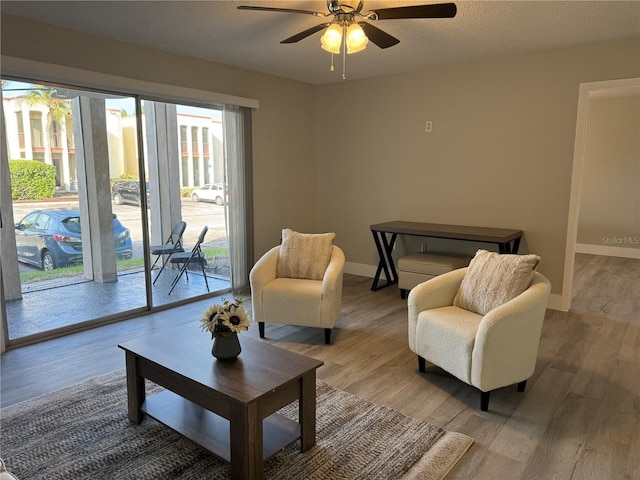 sitting room featuring a healthy amount of sunlight, a ceiling fan, baseboards, and wood finished floors