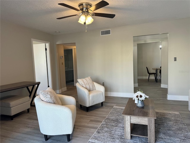 living room with baseboards, wood finished floors, visible vents, and a textured ceiling